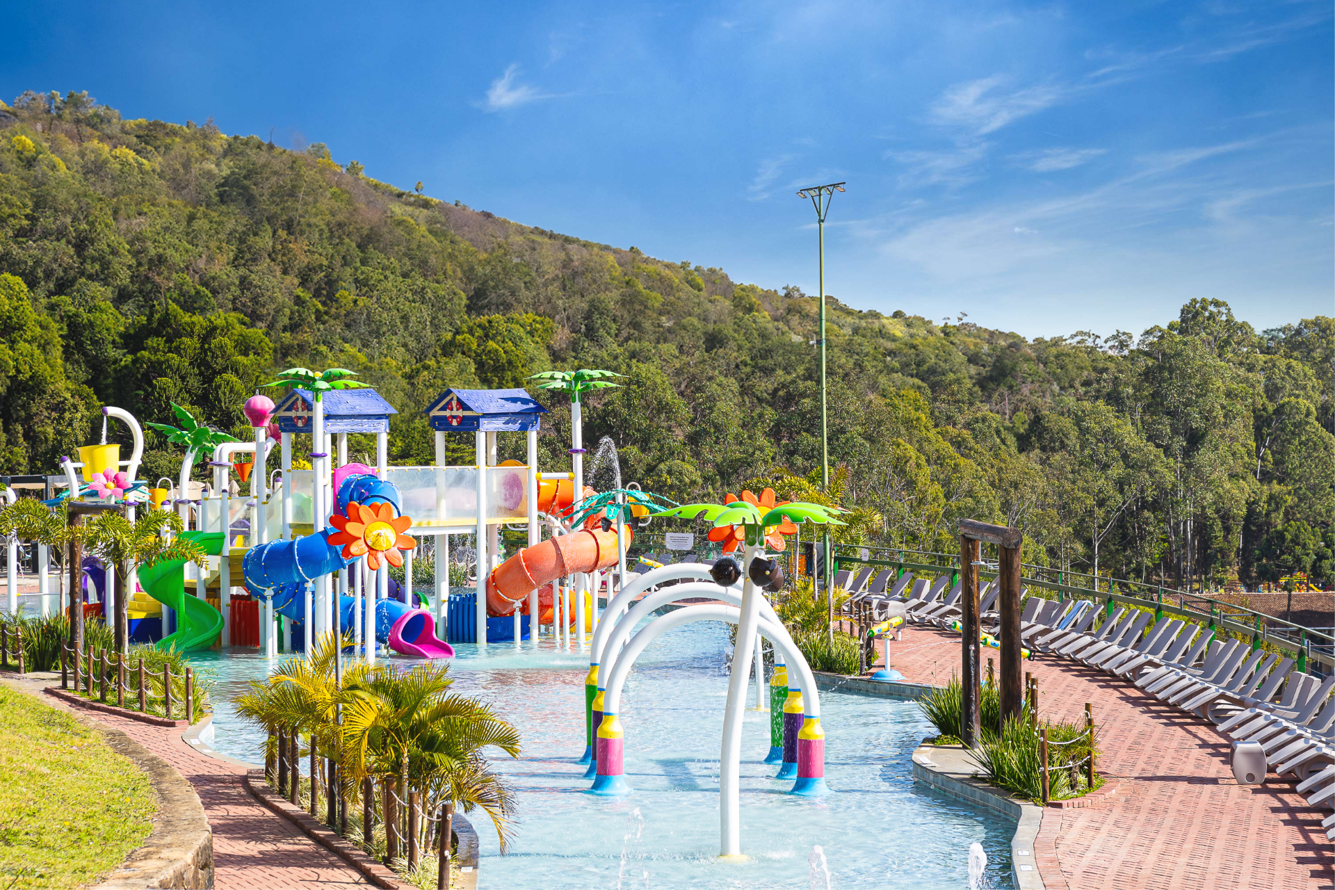 Área aquática infantil do Golden Park, com brinquedos coloridos e a serra ao fundo